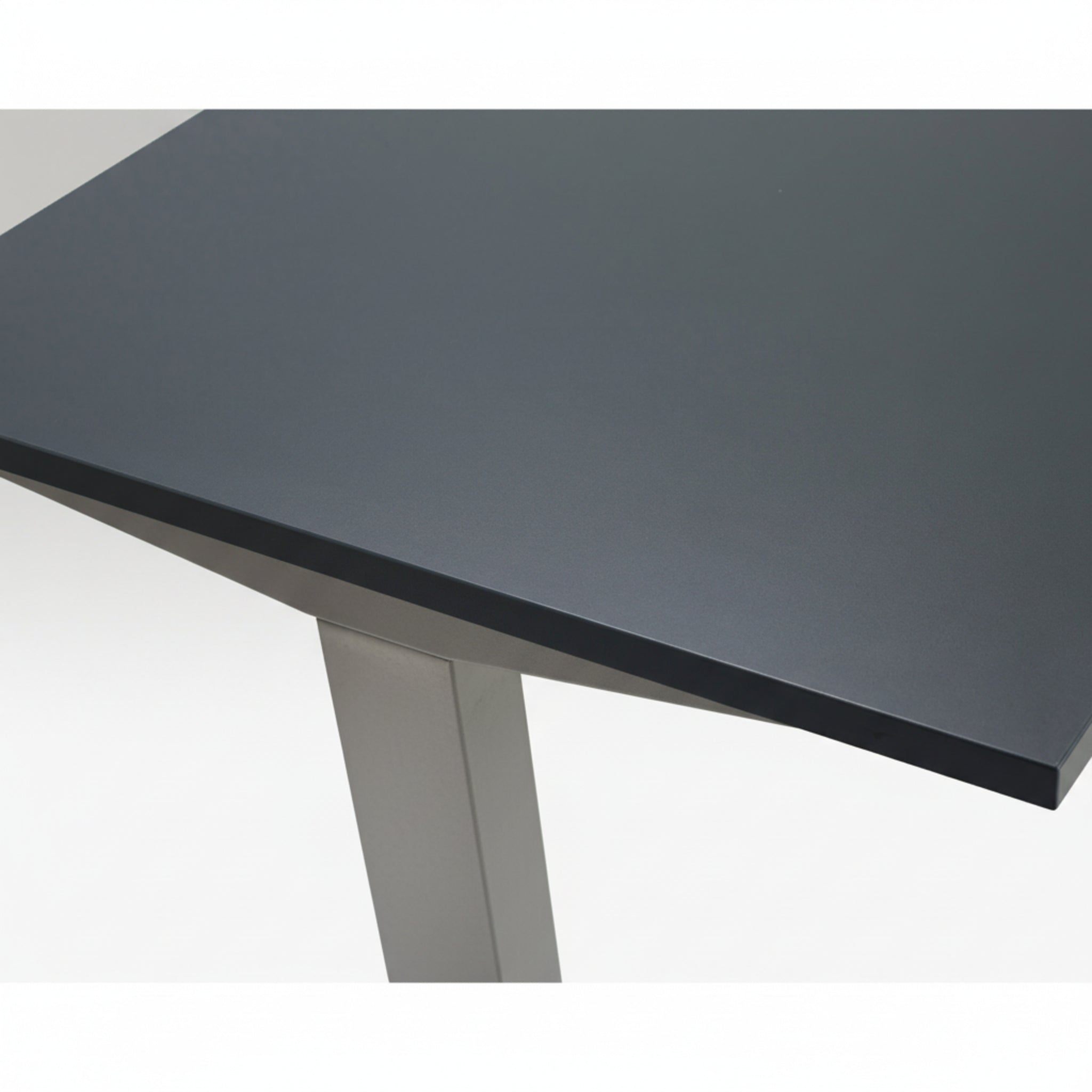 Close-up of Quiet Motor Standing Desk dark metal desktop and top of leg with raw steel finish