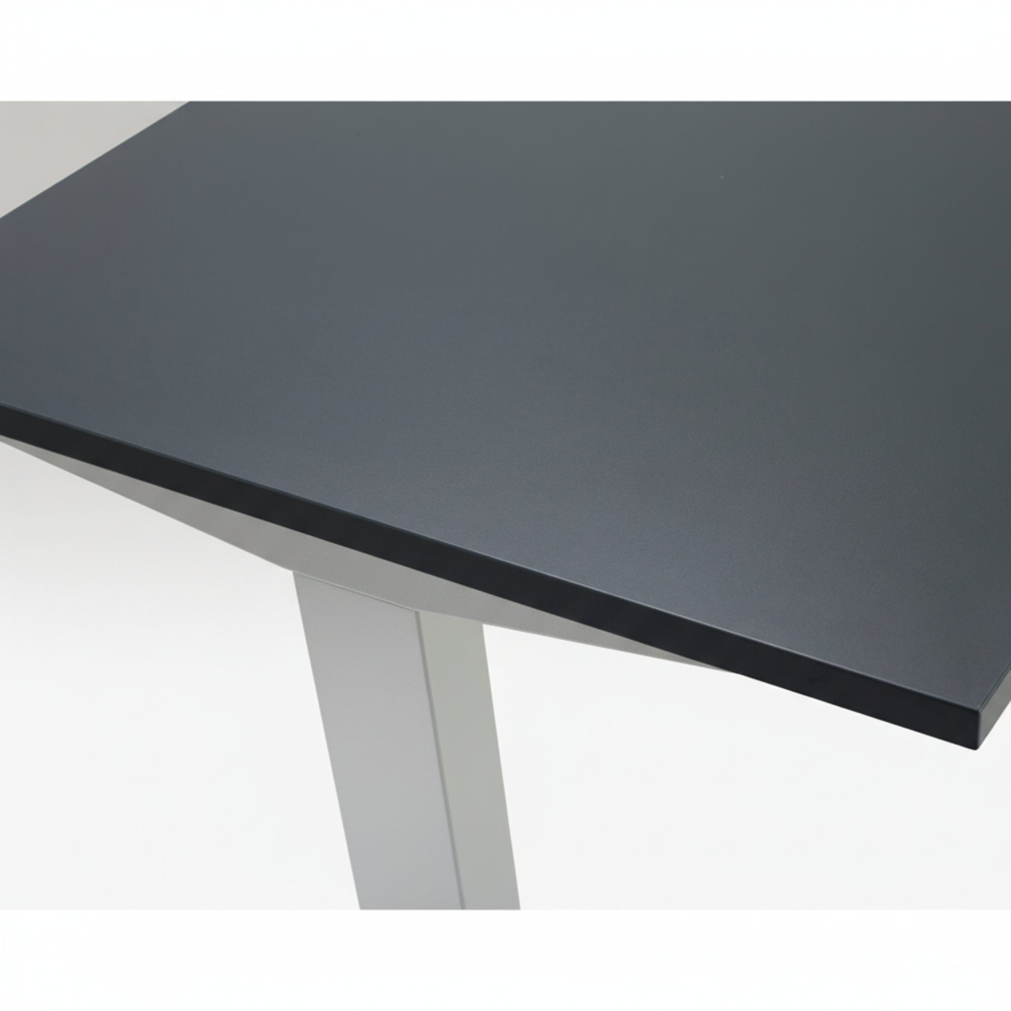 Close-up of Quiet Motor Standing Desk dark metal desktop and top of leg with silver finish