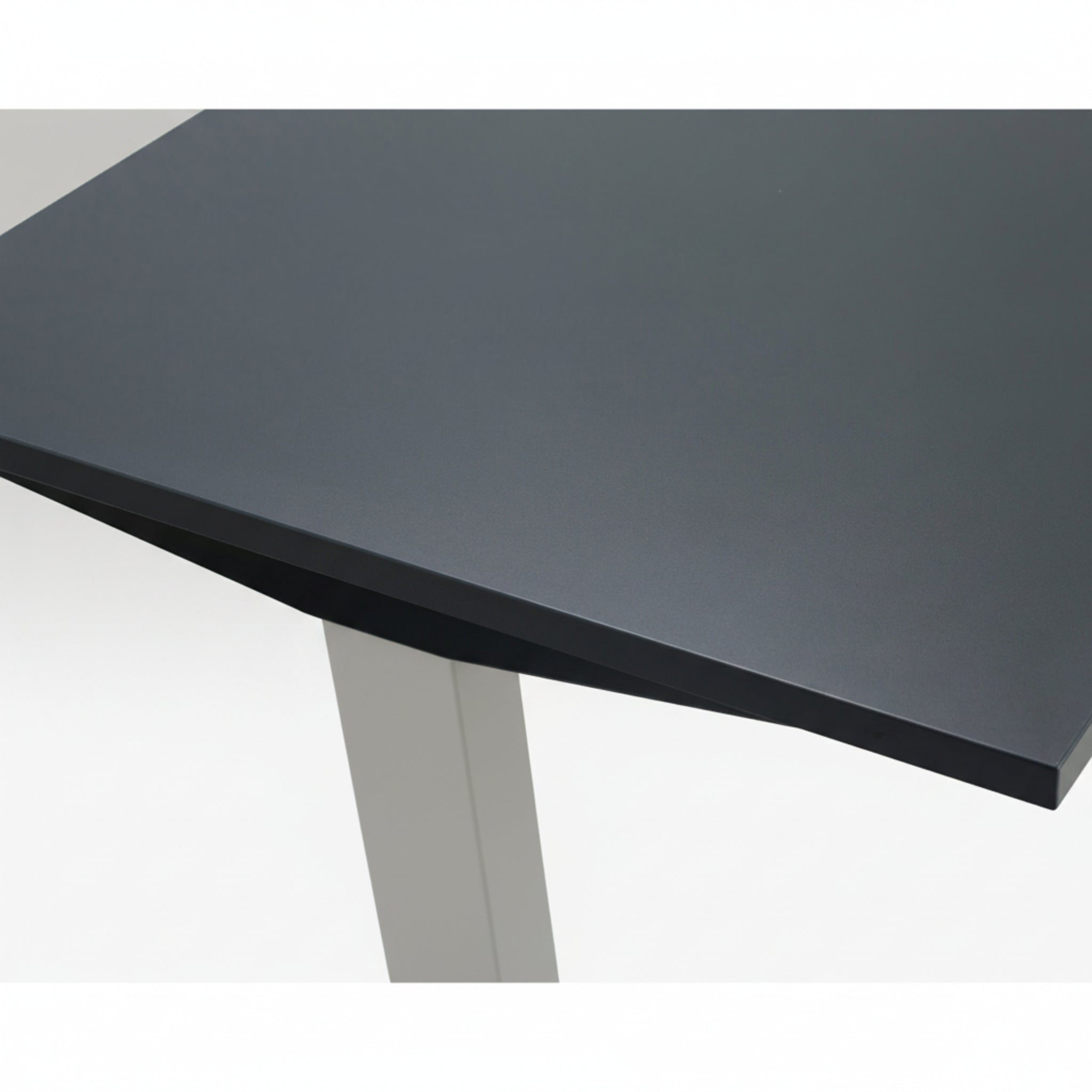 Close-up of Quiet Motor Standing Desk dark metal desktop and top of leg with light grey finish