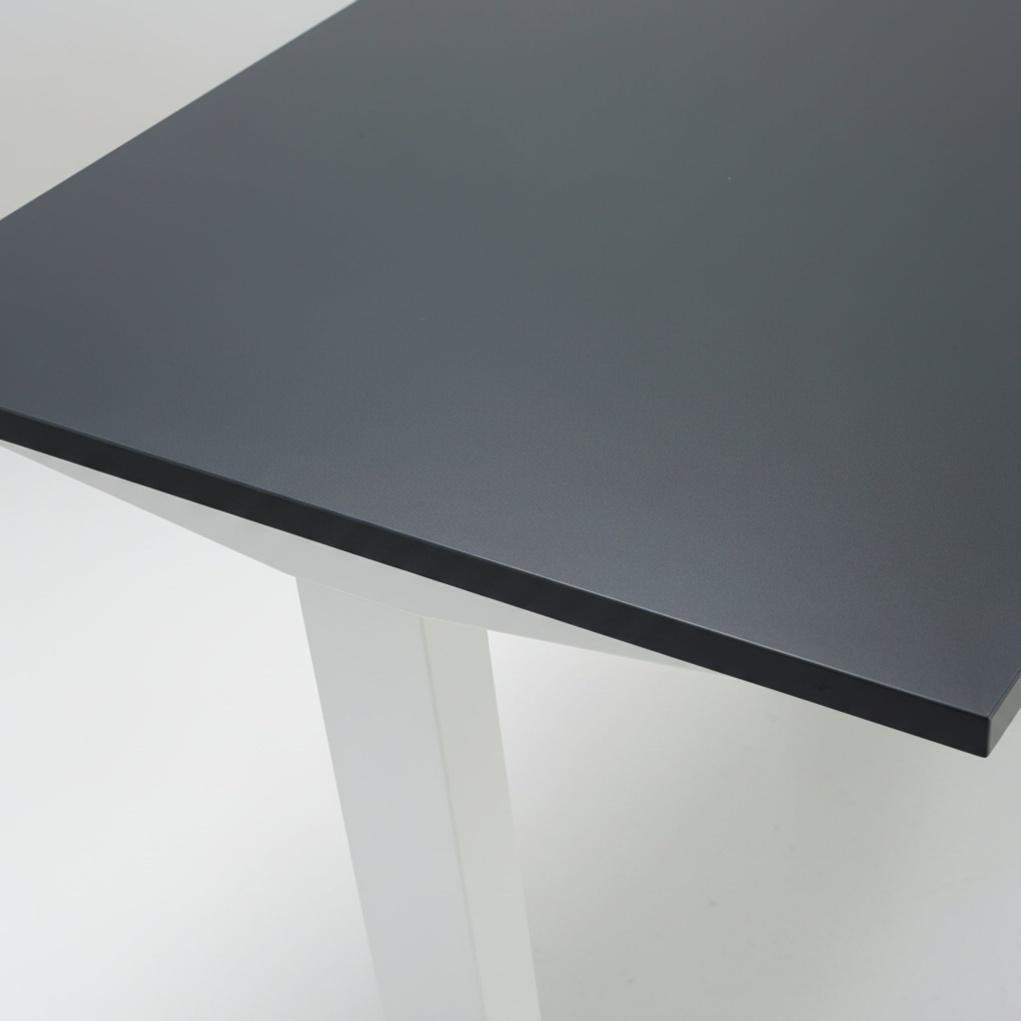 Close-up of Quiet Motor Standing Desk dark metal desktop and top of leg with white finish