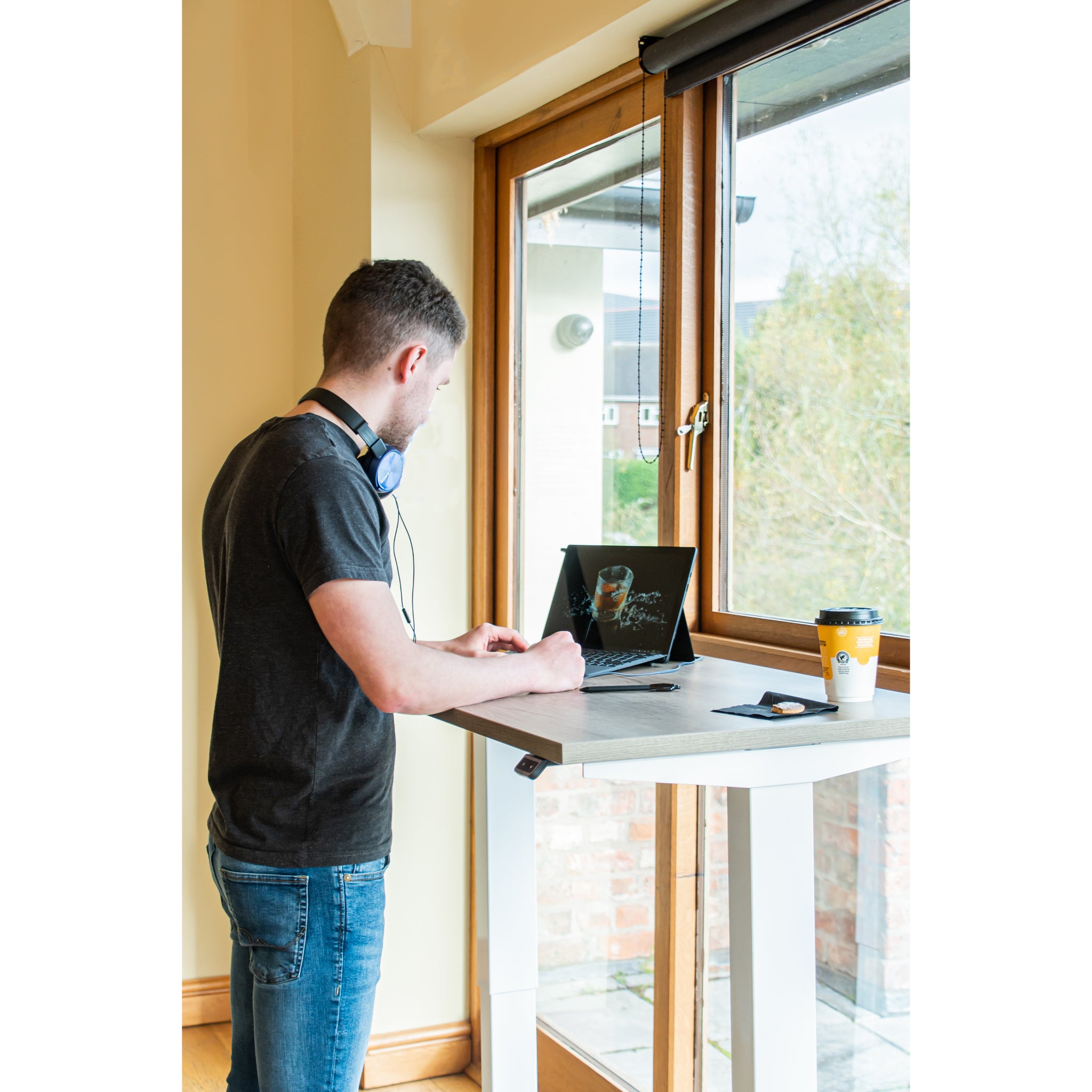 Person using a laptop on a standing desk in a bright room