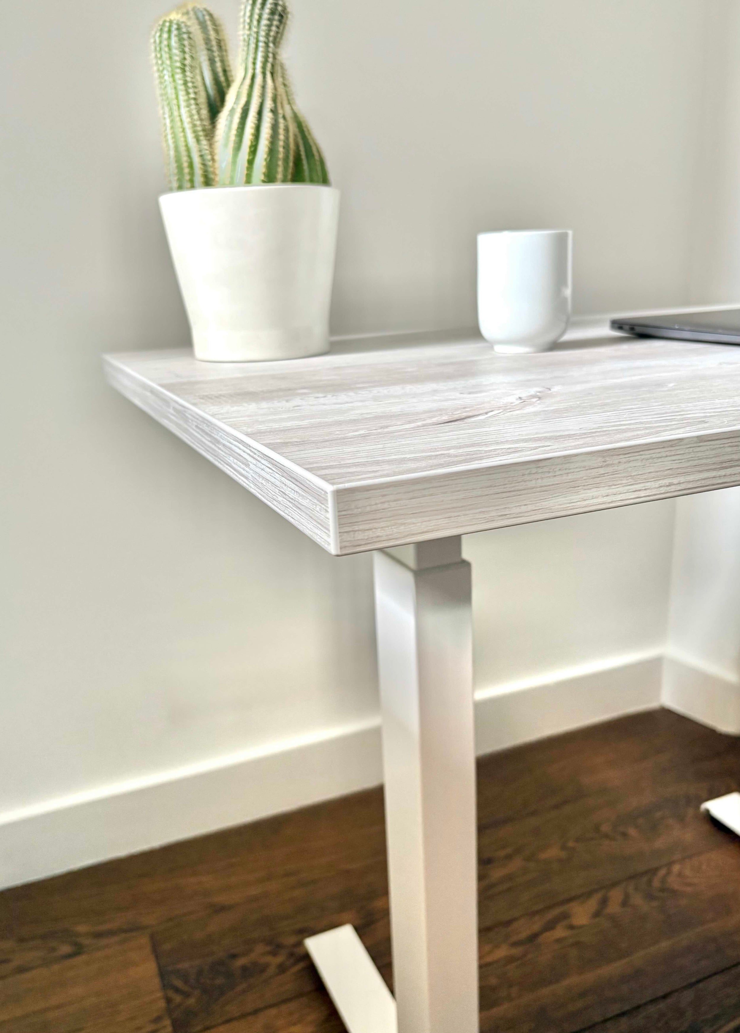 UrbanErgo Core standing desk with white frame and Casino Pine desktop shown at a 45 degree angle