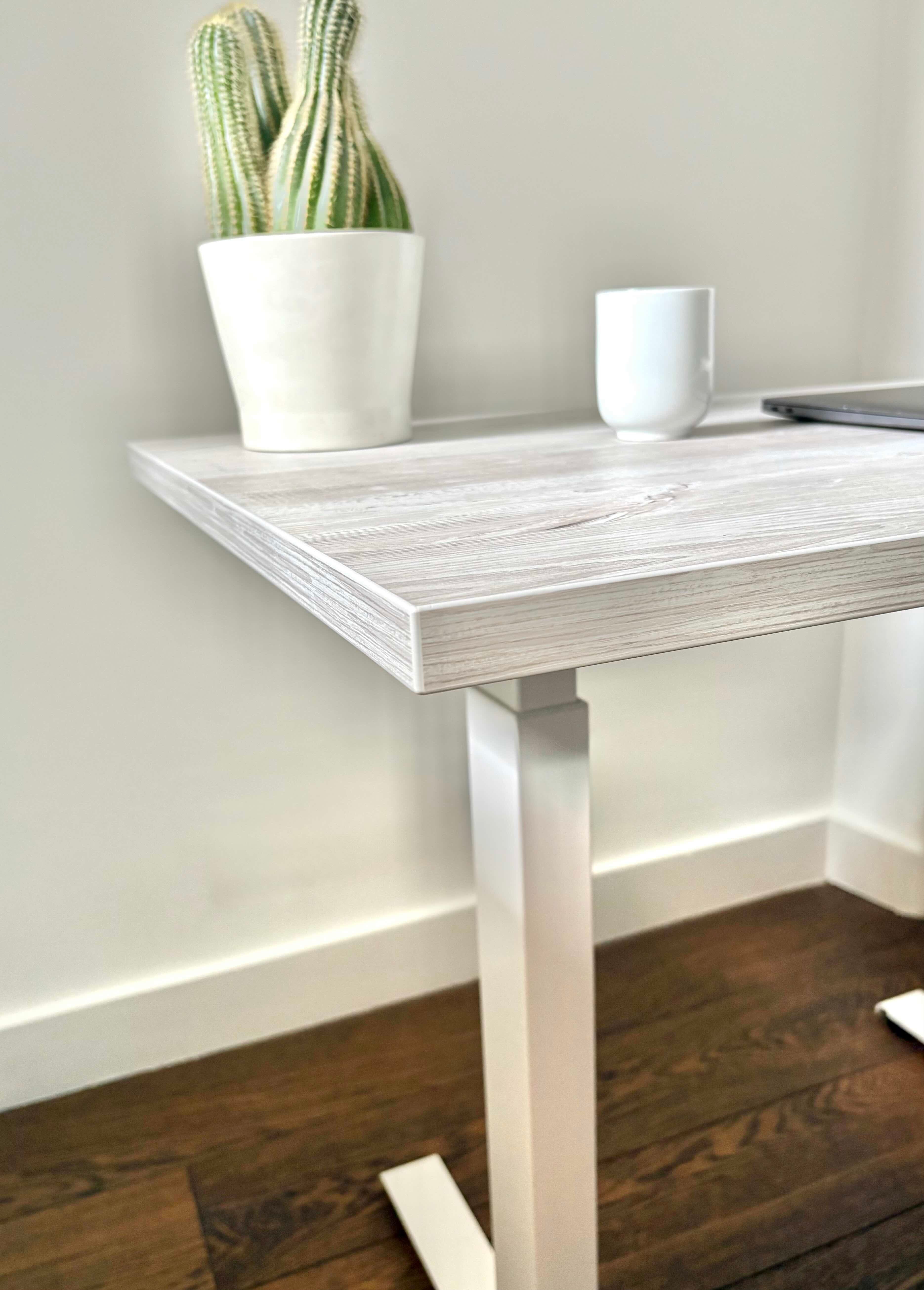UrbanErgo Core standing desk with white frame and Casino Pine desktop shown at a 45 degree angle