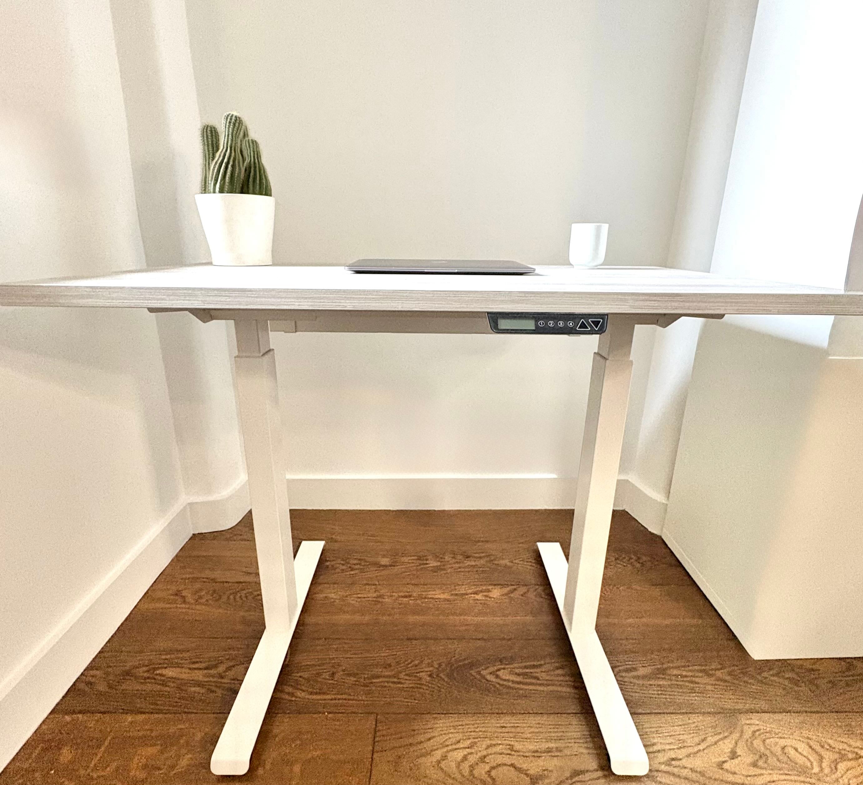 UrbanErgo Core electric standing desk with white frame and Casino Pine desktop styled in a compact home office
