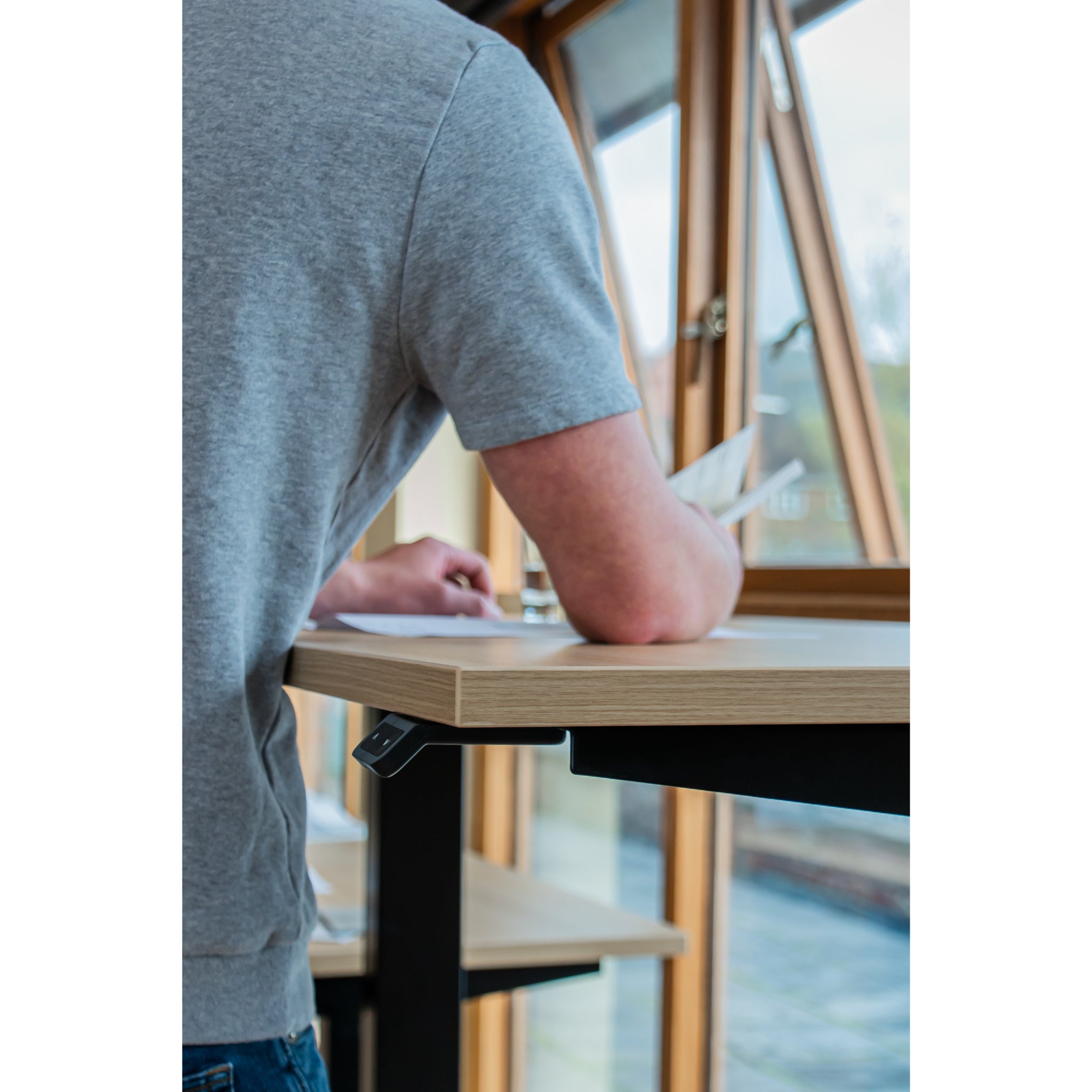Person working at the UrbanErgo Signature height-adjustable standing desk in standing position