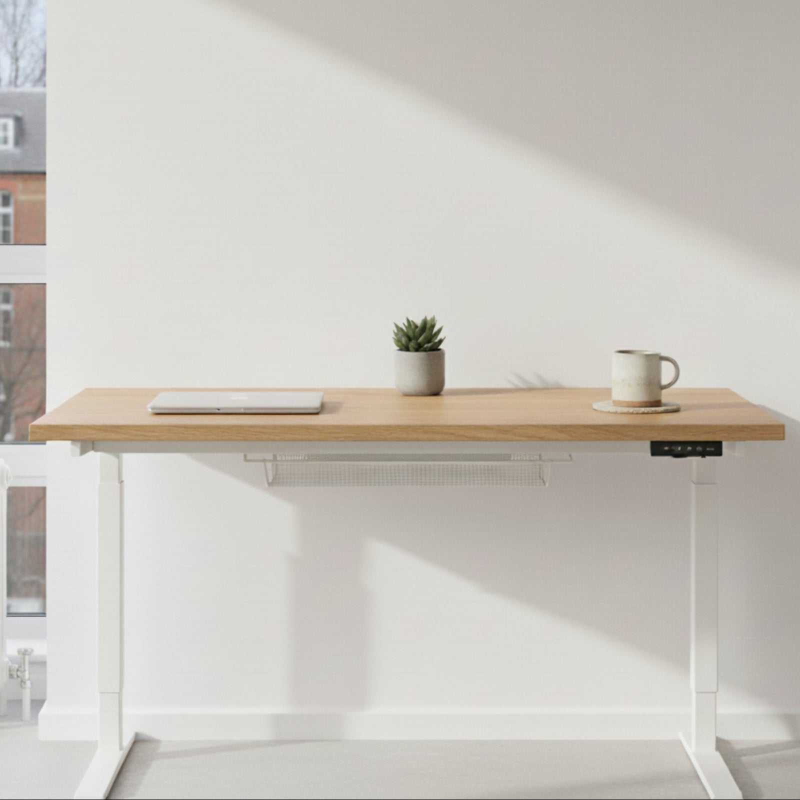Natural oak and white sit-stand desk in a bright London flat with minimal décor and soft daylight.